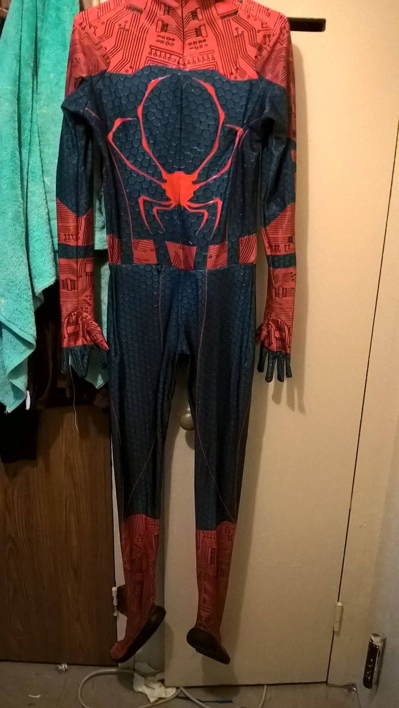 May include: A black and blue spandex jumpsuit with a red spider design on the back. The suit has a red and black circuit board pattern on the arms and legs.