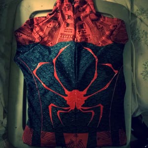 May include: A black and red spandex suit with a spider design on the back. The suit has a circuit board pattern on the front and back.