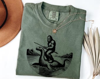 Bigfoot Riding Loch Ness Monster screen printed T-Shirt, Funny Cryptid Graphic Tee, Unisex Casual T-Shirt, Gift for Him, Comfort Colors