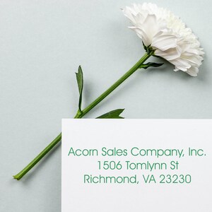 Elegant self-inking address stamp for weddings displayed on an envelope with a white flower. Perfect for adding a personal touch to invitations. Ideal self-inking stamp for envelopes, ensuring a stylish and efficient addressing solution.
