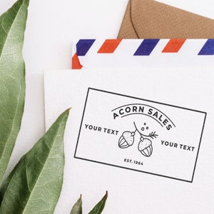 Personalized stamp featuring a business logo stamp design on a custom stamp pad, displayed with green leaves and an envelope. Ideal for branding and business identity.