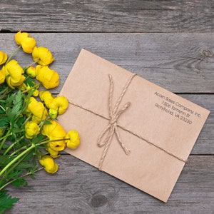 Customizable stamp with text on a mailing label stamp, featuring a minimalist 3-line stamp design on a brown envelope, tied with twine, placed on a rustic wooden surface with yellow flowers. Perfect for personalized mailing needs.