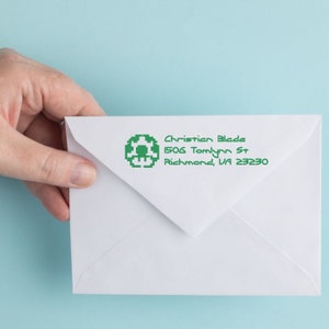 Personalized video game ink stamper on an envelope, showcasing a fun rubber stamp design. Ideal for gaming enthusiasts, this gaming stamp adds a playful touch to mail and stationery. Perfect for personalizing letters with a unique gaming flair.