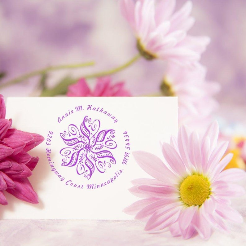 Custom rubber stamp featuring a floral design and personalized text, ideal as an address stamp for gifts. This custom self-inking address stamp adds a personal touch to any correspondence, surrounded by pink and white flowers.