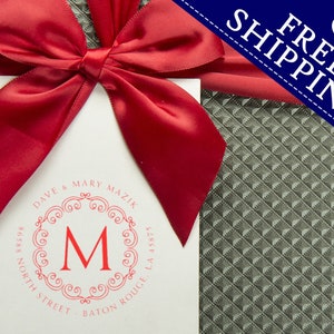 A personalized address stamp with a red monogram design is displayed on a gift package. The self-inking stamp offers convenience and style, perfect for adding a personal touch to your correspondence. Free shipping banner included.