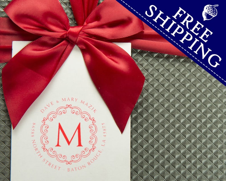 A personalized address stamp with a red monogram design is displayed on a gift package. The self-inking stamp offers convenience and style, perfect for adding a personal touch to your correspondence. Free shipping banner included.