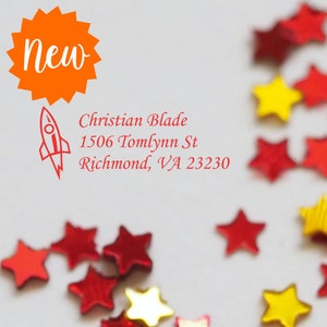 May include: A red rocket ship illustration with the text "New" in a bright orange starburst. The text "Christian Blade, 1506 Tomlynn St, Richmond, VA 23230" is written in red cursive font. The background is white with red and yellow star-shaped confetti.