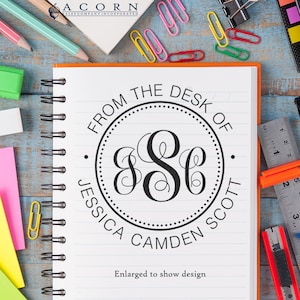 May include: A black and white personalized stamp with the text "From the Desk of Jessica Camden Scott" and the monogram "JCS" in a circle. The text "Enlarged to show design" is below the stamp.