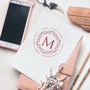 Housewarming gifts featuring personalized craft supplies and elegant home decor, including a custom monogram print, smartphone, and seashell, perfect for adding a personal touch to any space.