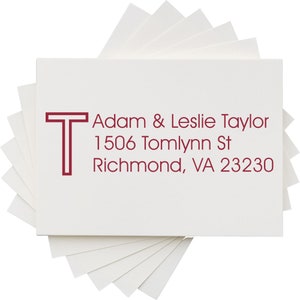 Personalized address stamp featuring a self-inking stamp design with a return address label for Adam & Leslie Taylor, 1506 Tomlynn St, Richmond, VA 23230, displayed on a stack of white cards. Ideal for efficient mailing.