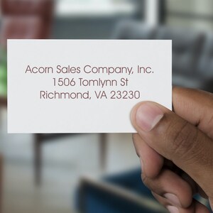 Hand holding a card with elegant calligraphy-style text, ideal for a personalized return address stamp. Perfect for creating a custom address stamp for home use, adding a touch of sophistication to your correspondence.