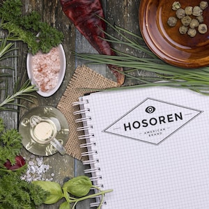 A custom stamper and small round rubber stamp are displayed on a rustic table with herbs and spices, ideal for creating custom stamps for business logos. Perfect for adding a personal touch to branding materials.