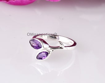 May include: A silver ring featuring two marquise-cut purple gemstones, set in a leaf-like design. The ring has a polished finish and is set against a white background. The text "OMganpaticraft" is visible.