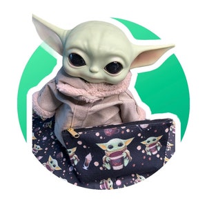 Puede incluir: Una bolsa negra con cremallera con un patr&oacute;n repetido de un personaje verde sosteniendo una taza. El personaje es similar a Baby Yoda de la serie Star Wars.