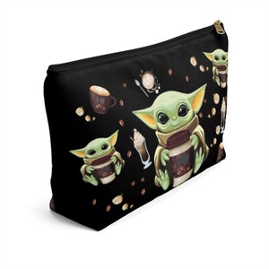 Puede incluir: Bolsa de maquillaje negra con cremallera con un patr&oacute;n repetido de un personaje alien&iacute;gena verde sosteniendo una taza de caf&eacute;, granos de caf&eacute; y una taza de caf&eacute; sobre un fondo negro.