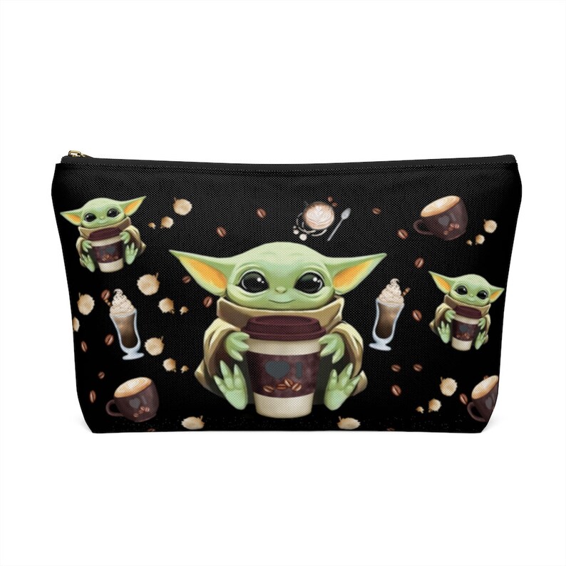 Puede incluir: Bolsa negra con cremallera con un patr&oacute;n repetido de un personaje alien&iacute;gena verde sosteniendo una taza de caf&eacute;, granos de caf&eacute; y tazas de caf&eacute;.
