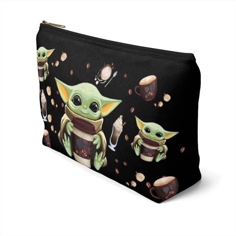Puede incluir: Bolsa de maquillaje negra con cremallera con un patr&oacute;n repetido de un personaje alien&iacute;gena verde sosteniendo una taza de caf&eacute;, una taza de cacao y granos de caf&eacute;.