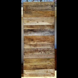 Puede incluir: Una pared o puerta r&uacute;stica de madera hecha de tablones de madera recuperada. Los tablones est&aacute;n dispuestos horizontalmente, mostrando una variedad de tonos de madera natural, incluyendo marr&oacute;n claro, dorado y tonos m&aacute;s oscuros, con vetas y nudos visibles.