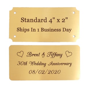 May include: Two gold metal plaques with engraved text. The top plaque reads "Standard 4" x 2" Ships In 1 Business Day". The bottom plaque reads "Brent & Tiffany 30th Wedding Anniversary 08/02/2020" with a heart symbol on each side of the names.