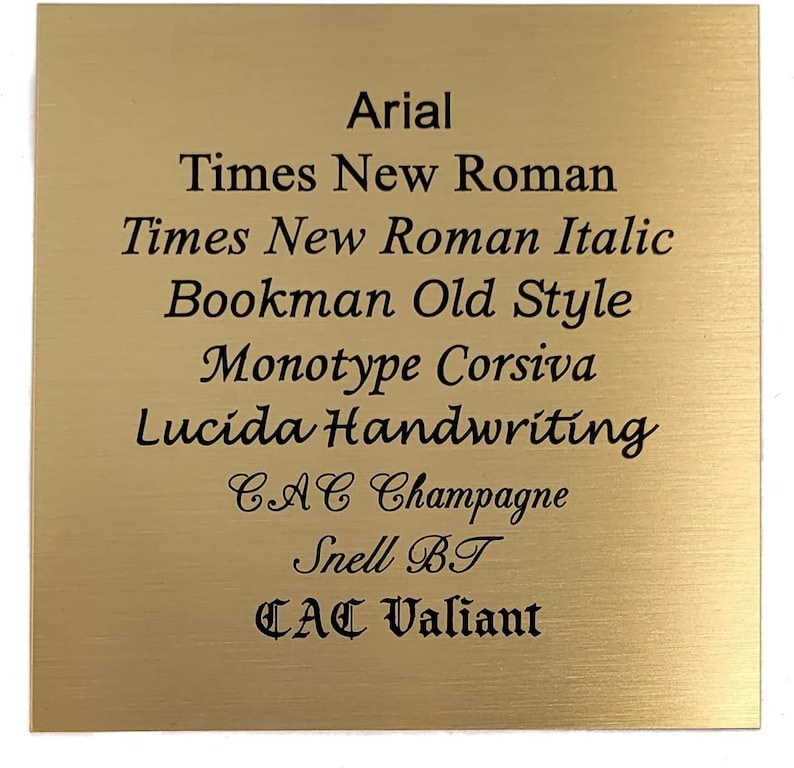 Puede incluir: Una placa de metal de color dorado con un acabado cepillado, que muestra una lista de diferentes nombres de fuentes en texto negro. Las fuentes que se enumeran son Arial, Times New Roman, Times New Roman Italic, Bookman Old Style, Monotype Corsiva, Lucida Handwriting, CAC Champagne, Snell BT y CAC Valiant.