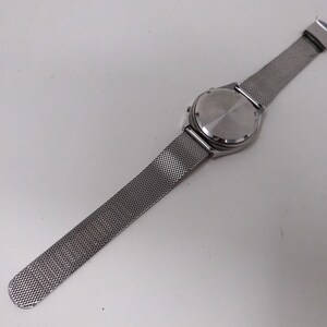 May include: A silver watch with a mesh metal band. The watch face is not visible in the image.