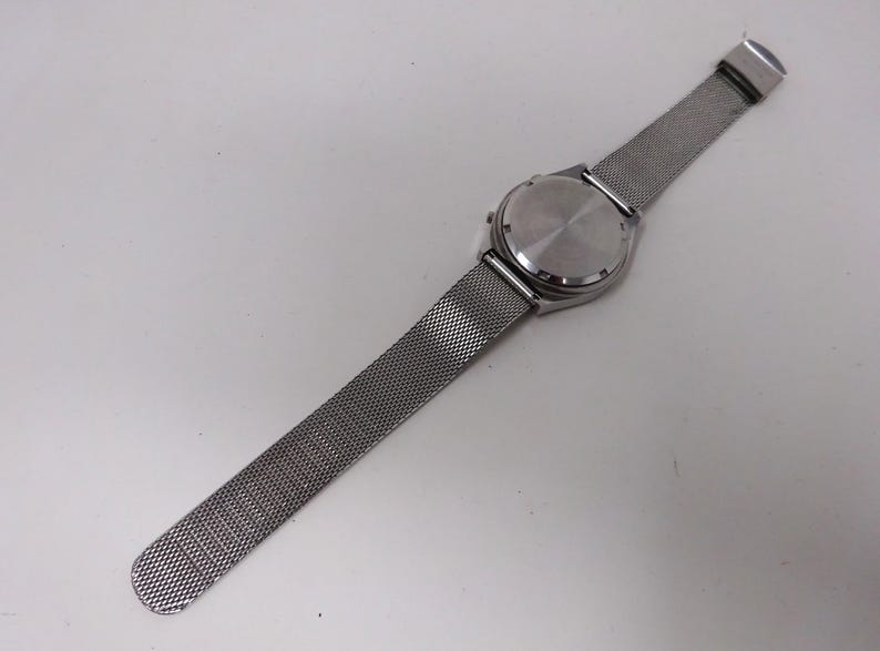 May include: A silver watch with a mesh metal band. The watch face is not visible in the image.