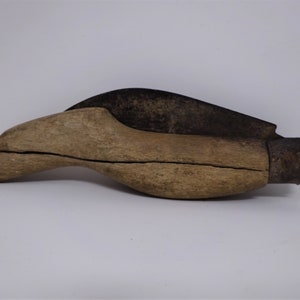 May include: A wooden shoe last with a metal tip. The last is brown and has a crack in the wood. The metal tip is black and has a worn finish.
