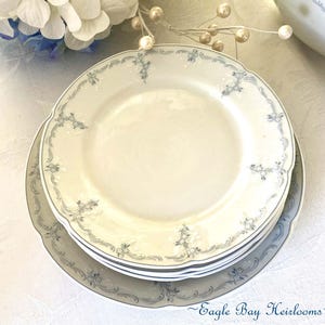 May include: Set of four white ceramic plates with a blue floral design. The plates are stacked on top of each other.