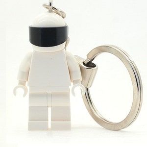 May include: White Lego minifigure keychain with a black visor and a silver keyring.