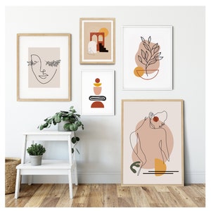 Op de afbeelding: Een set van zes minimalistische lijnkunstprints in witte frames. De prints tonen abstracte vormen, een gezicht, een plant en een figuur. De prints hangen aan een witte muur met een witte opstaptrede en een potplant ervoor.