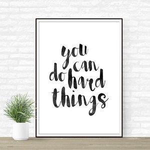 Op de afbeelding: Zwart-wit typografieprint met de tekst "You can do hard things" op een witte achtergrond in een zwart frame.