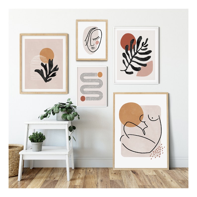 May include: Five framed abstract art prints with a minimalist style. The prints feature line drawings of a face, a leaf, a body, and geometric shapes. The prints are in shades of pink, brown, and orange.