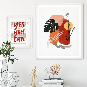 May include: Two framed prints, one with a motivational quote "yes you can" in red lettering and the other with an abstract design featuring a green leaf, orange and red brushstrokes, and a yellow sun.