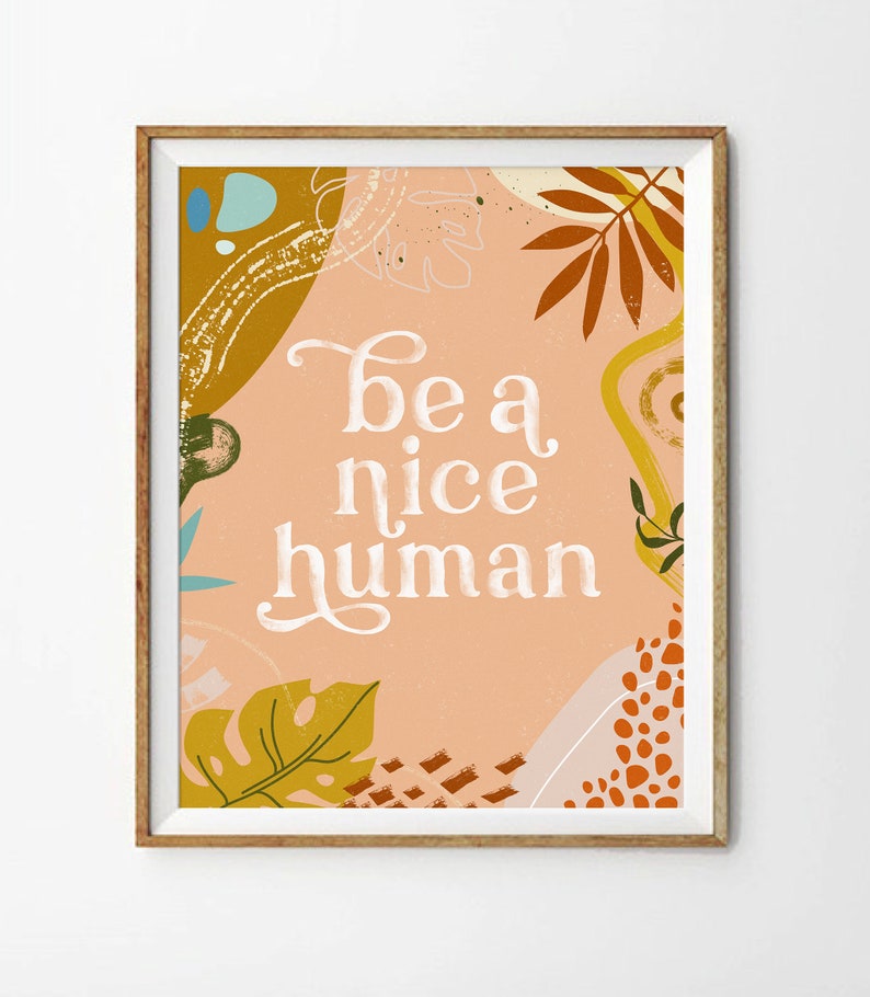 May include: A peach-colored poster with a white background and the text "be a nice human" in a white cursive font. The poster is decorated with abstract shapes and leaves in shades of orange, yellow, and green.