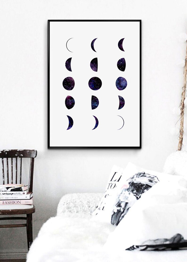 May include: A black framed print with a white background and a series of black and purple moons in different phases. The moons are filled with a galaxy-like pattern of stars.