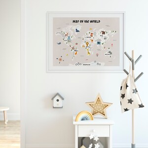 Puede incluir: Un mapa del mundo enmarcado en blanco con ilustraciones coloridas de animales y continentes. El mapa est&aacute; colgado en una pared blanca en una habitaci&oacute;n con una mesita de noche blanca, una estrella de madera y un arco&iacute;ris.