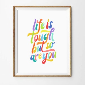 May include: A framed print with a colorful, handwritten quote that reads "life is tough but so are you".