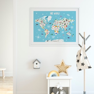 May include: A white framed world map print with colourful illustrations of animals and landmarks. The map is on a light blue background with the title "The World" at the top. The print is hanging on a white wall in a room with a white bedside table, a wooden star, and a rainbow.