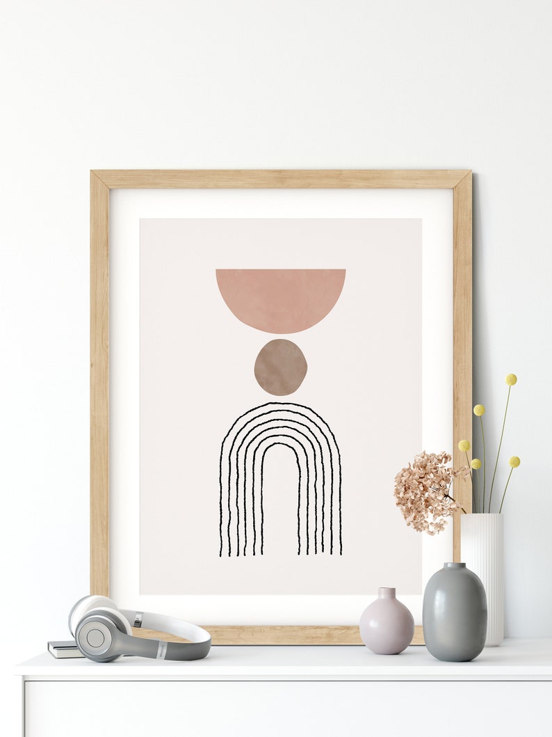May include: A framed print with a minimalist abstract design featuring a pink half-circle, a brown circle, and a black and white rainbow-like arch.