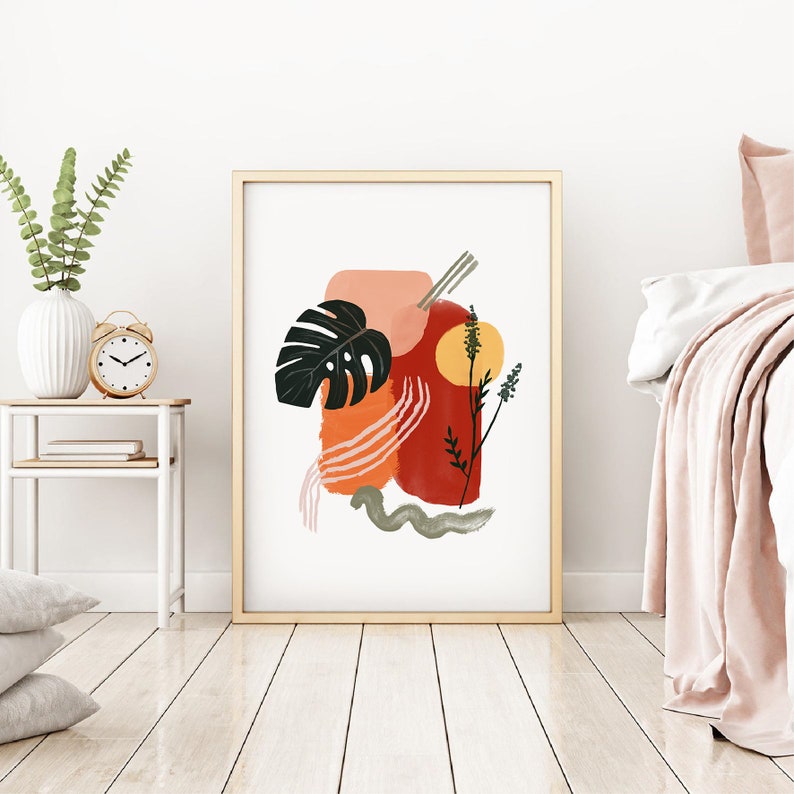 May include: Abstract art print with a large green leaf, red, orange, and pink shapes, and a yellow circle. The print is framed in a light wood frame.