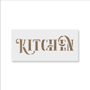 May include: A rectangular stencil with the word "KITCHEN" cut out in a decorative font. The letters are a textured, light brown color, and the stencil itself is white. The design is centered on the stencil.