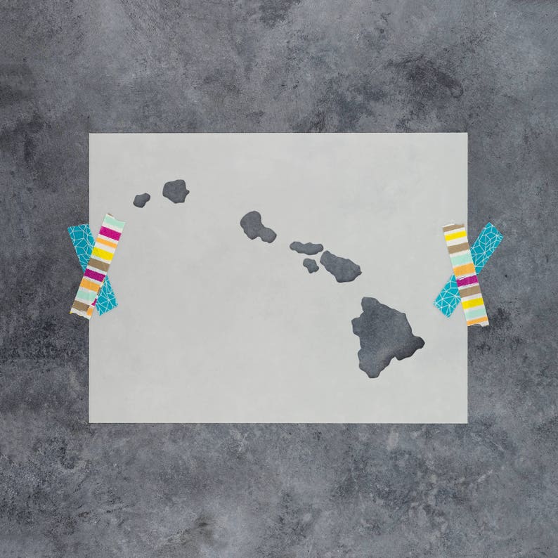 May include: A white stencil of the Hawaiian islands, taped to a gray textured surface. The stencil is shaped like the islands of Hawaii, with the main island of Hawaii being the largest.