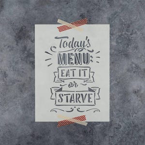 May include: A rectangular stencil featuring the text Today's MENU: EAT IT or STARVE in a decorative, bold font. The stencil is white with dark gray lettering and is secured at the top and bottom with strips of red and white polka dot tape.