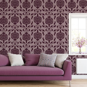 May include: A purple sofa with two white pillows and one patterned pillow sits in front of a wall with a repeating pattern of burgundy pomegranates.