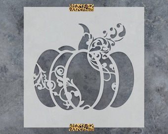 May include: A square stencil featuring a pumpkin design with intricate filigree and scrollwork patterns cut out of the center. The stencil is held in place by two strips of leopard print tape at the top and bottom edges of the square sheet.