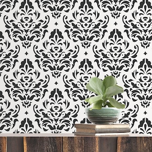 May include: A black and white damask patterned wallpaper featuring a repeating symmetrical floral motif. The design consists of intricate, stylized leaf and scroll shapes arranged in a vertical grid, creating a high-contrast graphic surface.