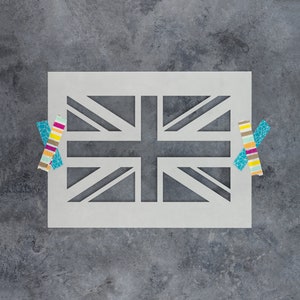 May include: A white stencil of the Union Jack flag on a gray background. Two colorful washi tape strips are on either side of the stencil.