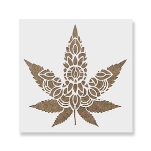 May include: A white stencil of a detailed mandala-style cannabis leaf on a brown background.