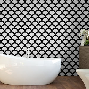 May include: A white bathtub sits in front of a wall with a black and white geometric pattern. The pattern resembles fish scales.