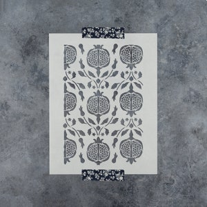 May include: A white stencil with a repeating pattern of pomegranates and leaves. The stencil is made of a thin, flexible material and is designed for use with paint or other mediums.